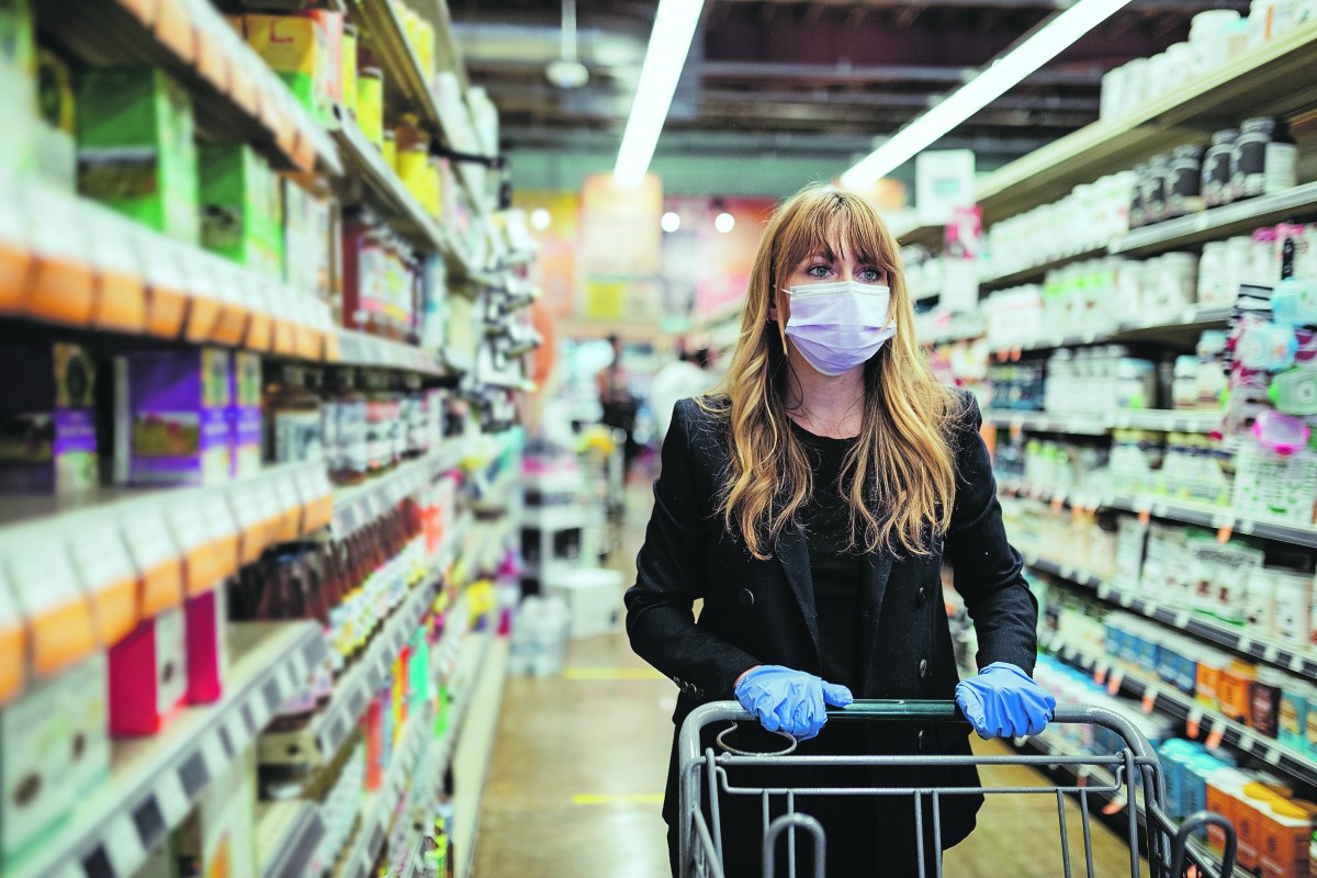 Vrouw met mondmasker en handschoenen in de winkel