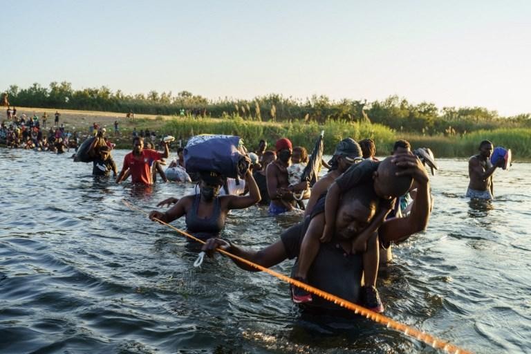 mensen uit Haiti steken een rivier over