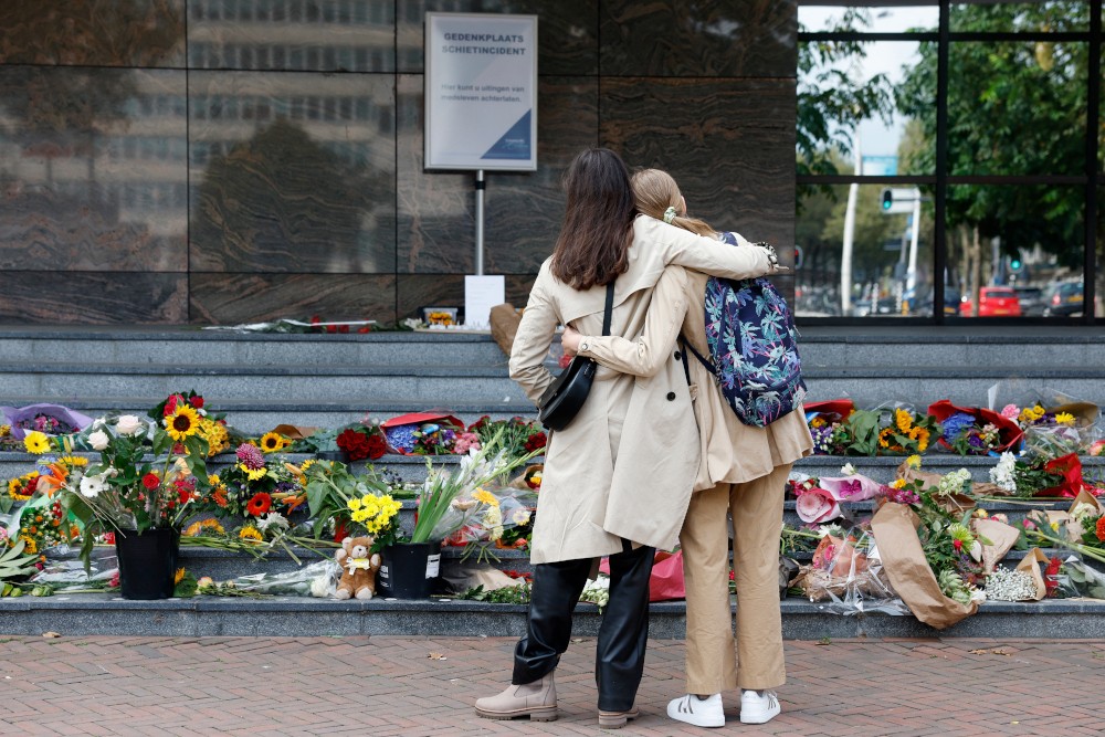 mensen rouwen bij bloemen aan een ziekenhuis